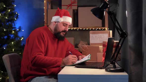 Dropshipping Owner Male Hindu Santa Claus Works at Home Office at Night on Laptop Checks Order for alt