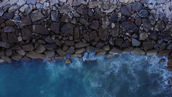 Aerial Overhead View Of Waves Crashing Into Breakwater At Catalan Bay In Gibraltar. alt