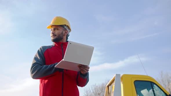 Young Engineer Using Laptop Standing At The Field Working On His Laptop alt