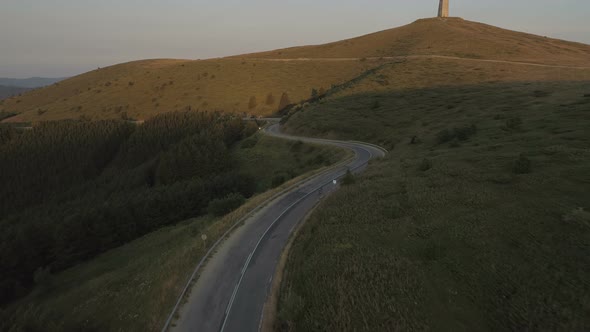 Drone Following Energetic Cyclist Speeding Down Asphalt Mountain Road at Sunset alt