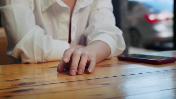 Closeup of the Girl's Hand She Taps Her Fingers on the Table in Anticipation of Another Person alt