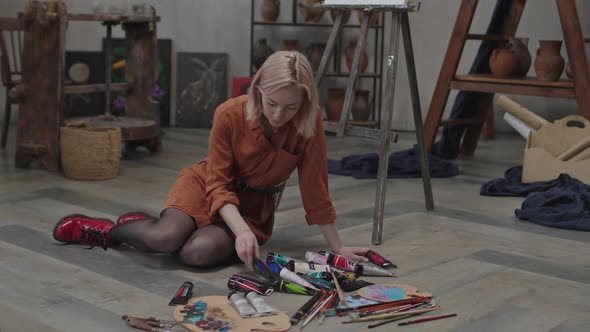 Female Artist Choosing Acrylic Paints for Picture alt