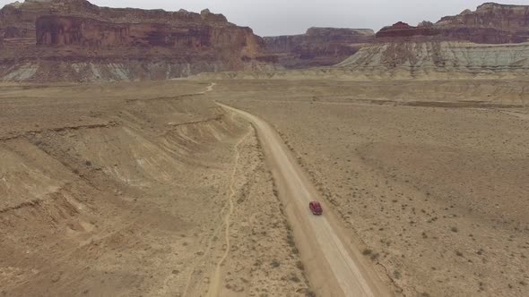 Aerial view following truck driving on dirt road through the Utah desert alt