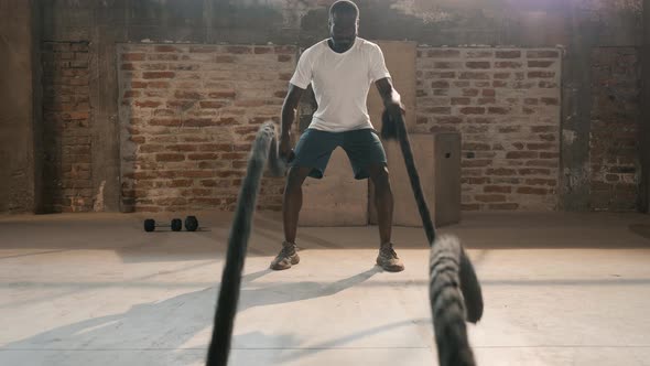 Sport man doing battle ropes exercise workout at gym alt