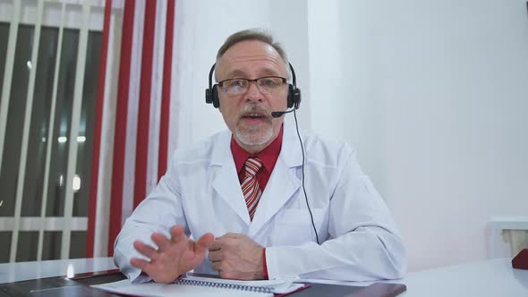 Medical specialist in headset talks on camera. alt