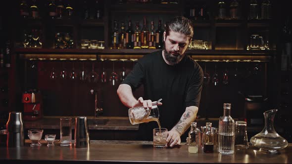 Barkeep Pours Finished Cocktail Into Glass Using Strainer alt