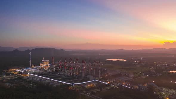 Aerial view over coal-fired power plant at sun dawn with smoke from cooling, alt