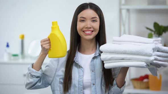 Smiling Woman Showing Clean Towels and Laundry Detergent, Fabric Softener alt