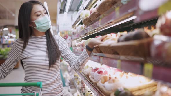 Young Asian woman in medical mask grocery walk toward camera shot, at supermarket alt