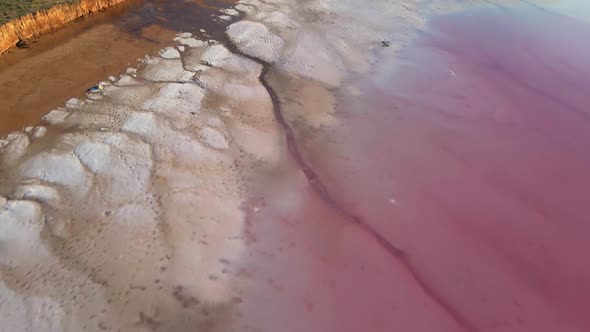 Drone Flight Over Red Clay Coast of Pink Lake with Salt Deposits alt