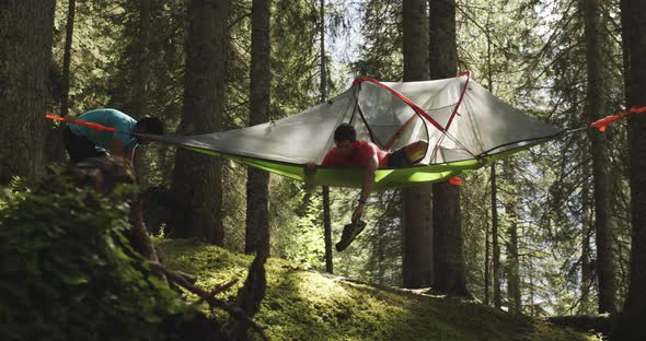 Two Men Camping with Hanging Tent in Sunny Forest