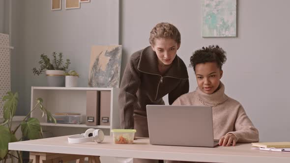 Female Colleagues Discussing Presentation on Laptop alt