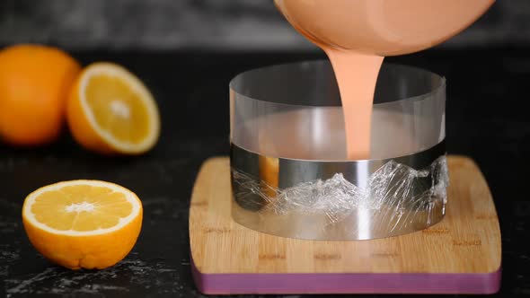 A Pastry Chef Woman Pours Orange Mousse Into a Pastry Ring
