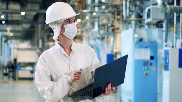 Female Specialist in Safety Wear is Observing Factory Constructions alt