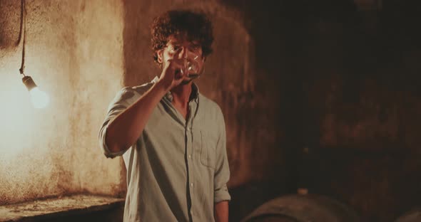 Young man raising his arm to toast with red wine in a tradtional wine cellar alt
