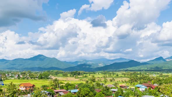 Rice paddy farming filed and village at Pua district Nan province, Thailand; zoom out - time lapse