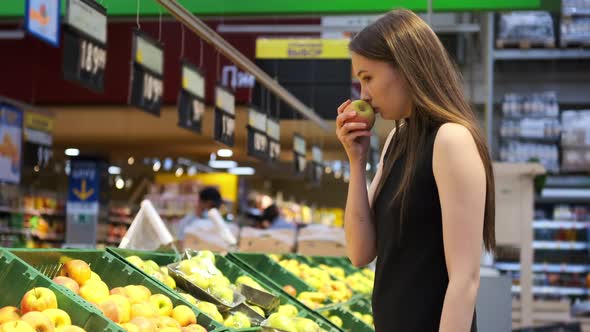 Woman is Choosing Apples in Fruit Department in Supermarket alt