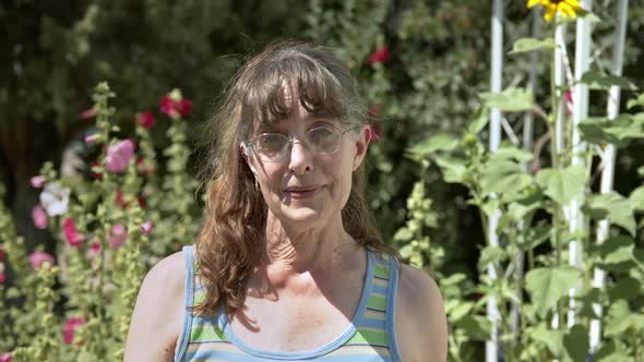 Country woman standing in front of flowers and smiling alt