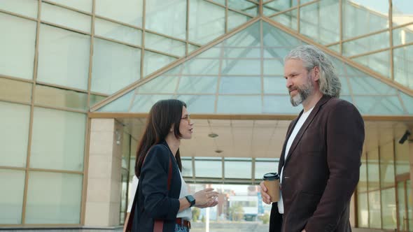 Slow Motion Portrait of Male and Female Business Partners Talking Standing Near Glass Walls Building alt