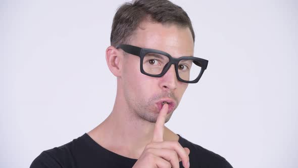 Studio Shot of Happy Nerd Man with Finger on Lips alt