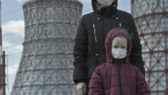 Mom with a Little Girl in Masks on the Background of a Thermal Power Plant