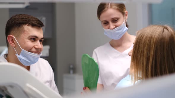 Young Happy Woman Client Looking at the Mirror with Toothy Smile at the Dental Office alt