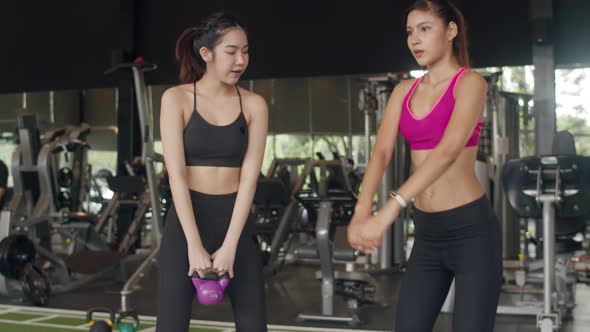 Asian lady personal trainer focus on body weight training squat with heavy ball to lady customer.
