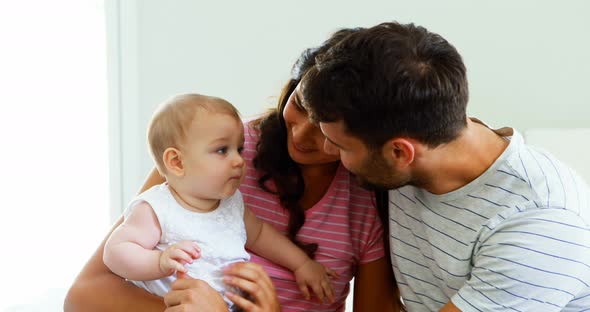 Parents playing with their baby girl in bedroom alt