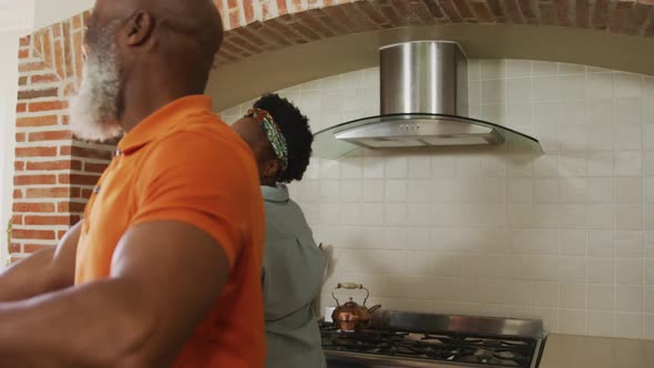 African american senior couple dancing together in the kitchen at home alt