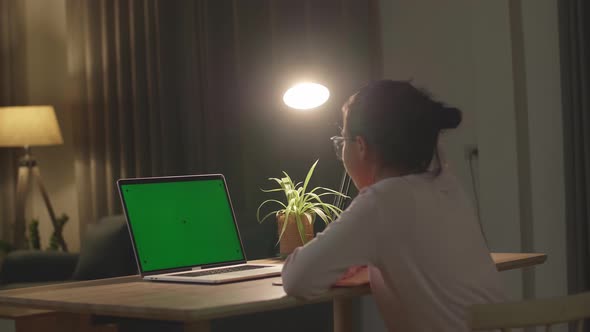 Teenage Girl Sitting At Her Desk Learning Online On A Laptop With Green Mock-Up Screen alt