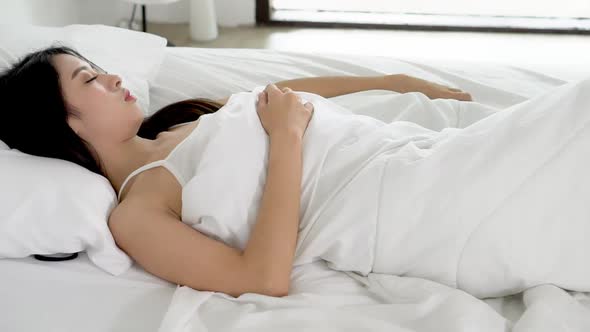 Young asian woman sleeping lying in bed with head on pillow comfortable. alt