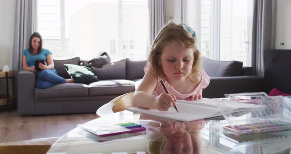 Caucasian girl drawing in notebook in living room alt