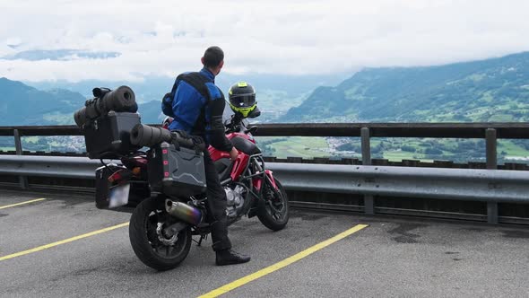 Biker on Tourist Motorbike with Luggage Bags Stands By Mountain Landscape Alps alt
