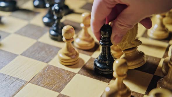 Capturing a white knight by a black bishop in a chess game. Man hand with a chess piece in a board