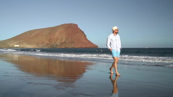 Happy Man Walking Along the Ocean Beach at Sunset alt