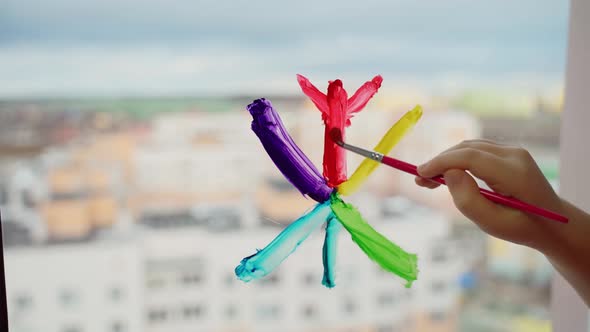 Child draw snowflake in rainbow colours on window with paints. Caucasian female person decorate room alt
