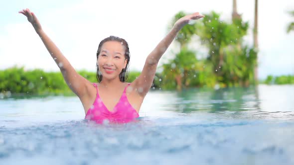 Young asian woman enjoy around outdoor swimming pool for leisure alt