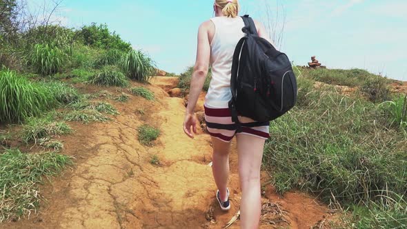 traveler girl walking along a trail on a tropical island with palm trees and sea alt