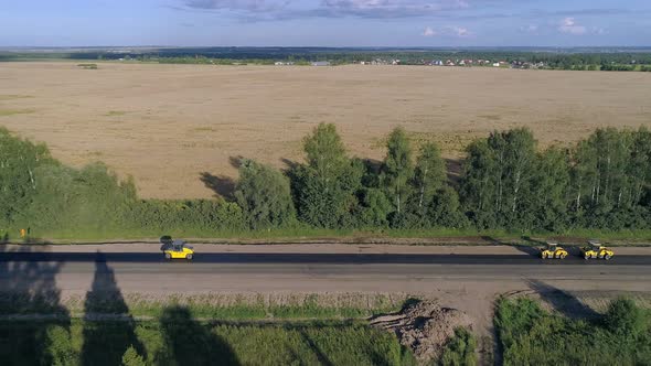 Road roller doing repair and paving of road amoung the fields alt