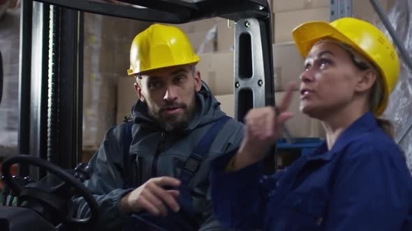 Forklift Operator Discussing Work with Female Colleague alt