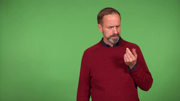 A Middleaged Man Picks His Teeth and His Nose Then Wipes His Fingers Into His Sweater Green Screen