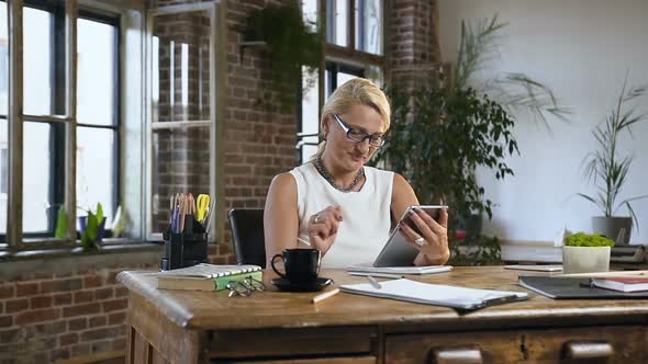 Middle-aged Blonde Sitting at a Wooden Table in Classical Style Office alt