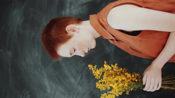 Redhead Woman Holding Yellow Wildflowers in Studio alt