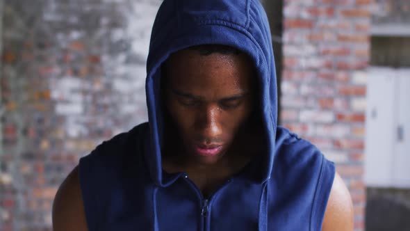 Portrait of african american man wearing hoodie sweating after exercise looking at camera in urban b alt