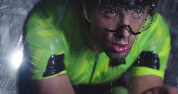 Triathlon Athlete Riding a Professional Racing Bicycle on an Intense Workout in Dark with Rain