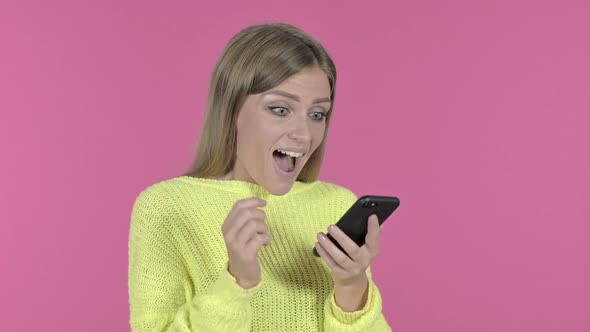 Excited Girl Cheering Success While Using Smartphone Pink Background alt
