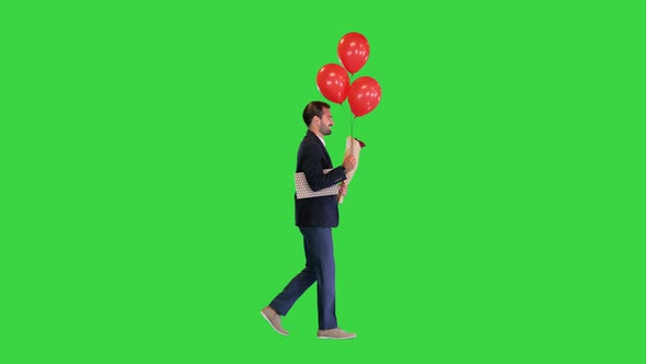 Elegant Man in a Suit with a Bouquet of Flowers a Gift and Balloons Walking on a Green Screen Chroma alt
