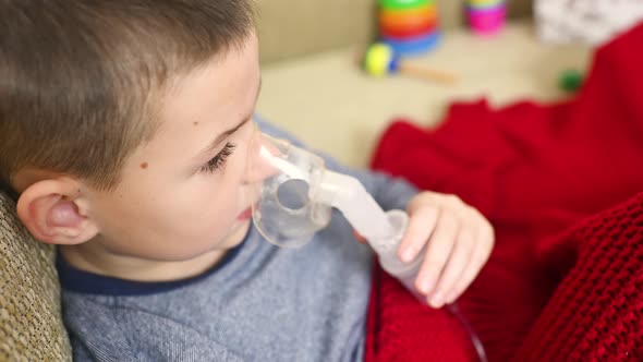 Child Teenager Boy Breathes Through an Inhaler or Nebulizer alt