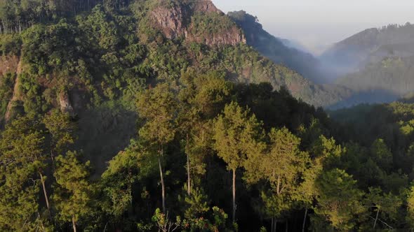 Aerial view of sunrise at mountain top with fog and clouds down in the mountain valley