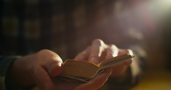 Close-up, the Guy Is Sitting in the Library and Flipping the Pages of a Very Small Book in the alt